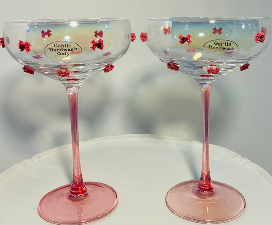 Set of 2 Iridescent pink coupe glasses feature a stem-to-base ombré effect decorated w/red bows 7”