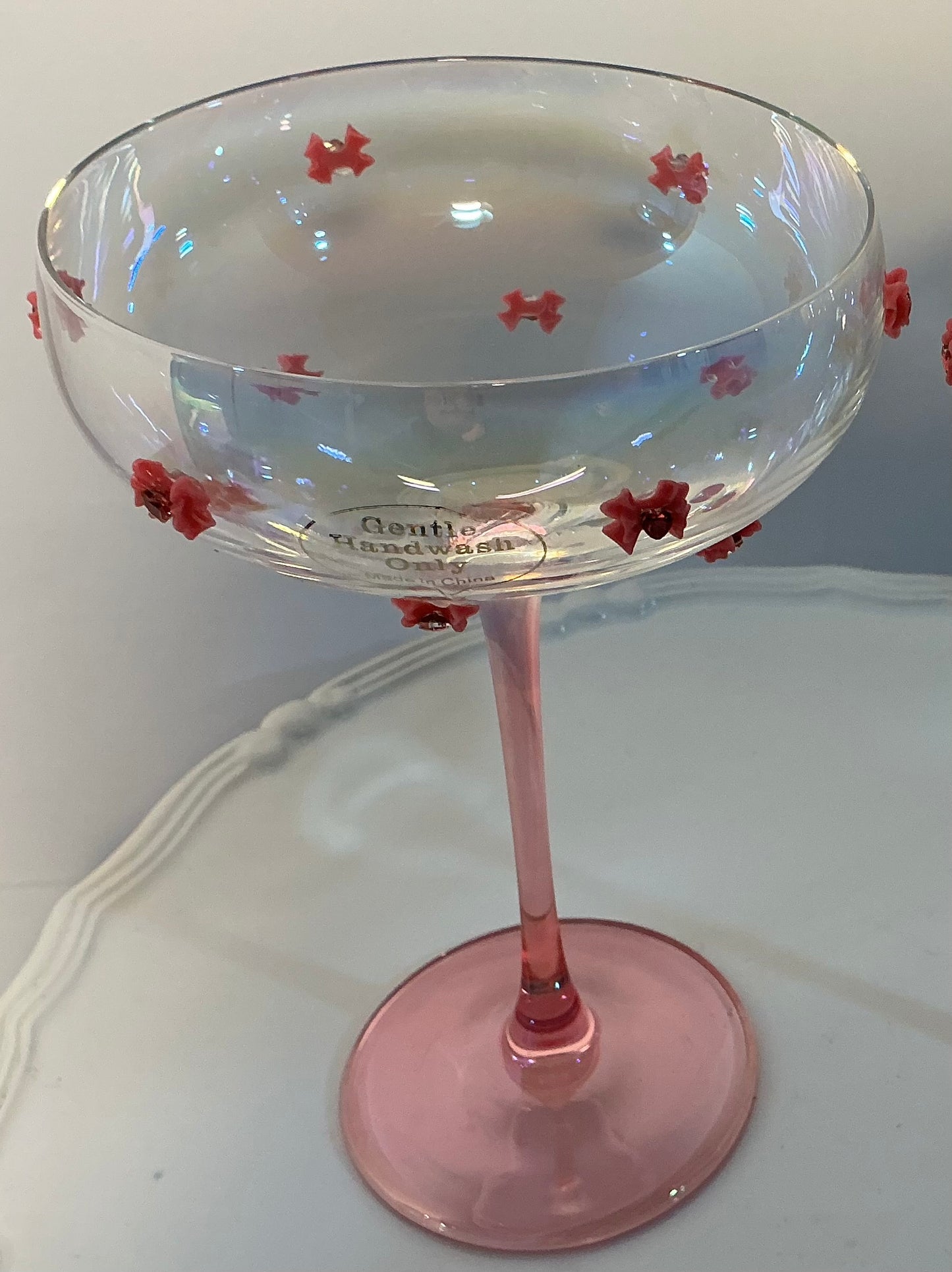 Set of 2 Iridescent pink coupe glasses feature a stem-to-base ombré effect decorated w/red bows 7”