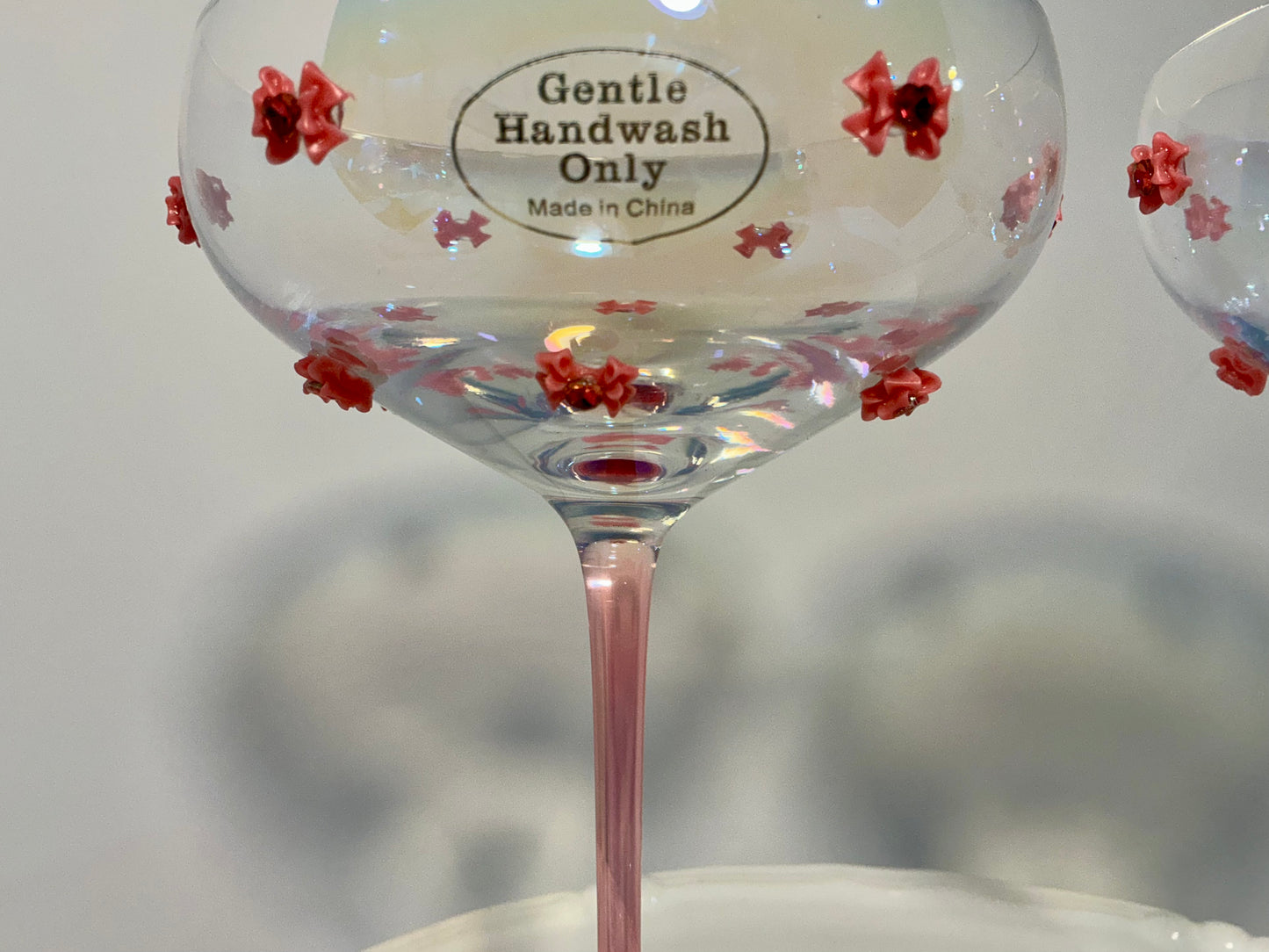 Set of 2 Iridescent pink coupe glasses feature a stem-to-base ombré effect decorated w/red bows 7”