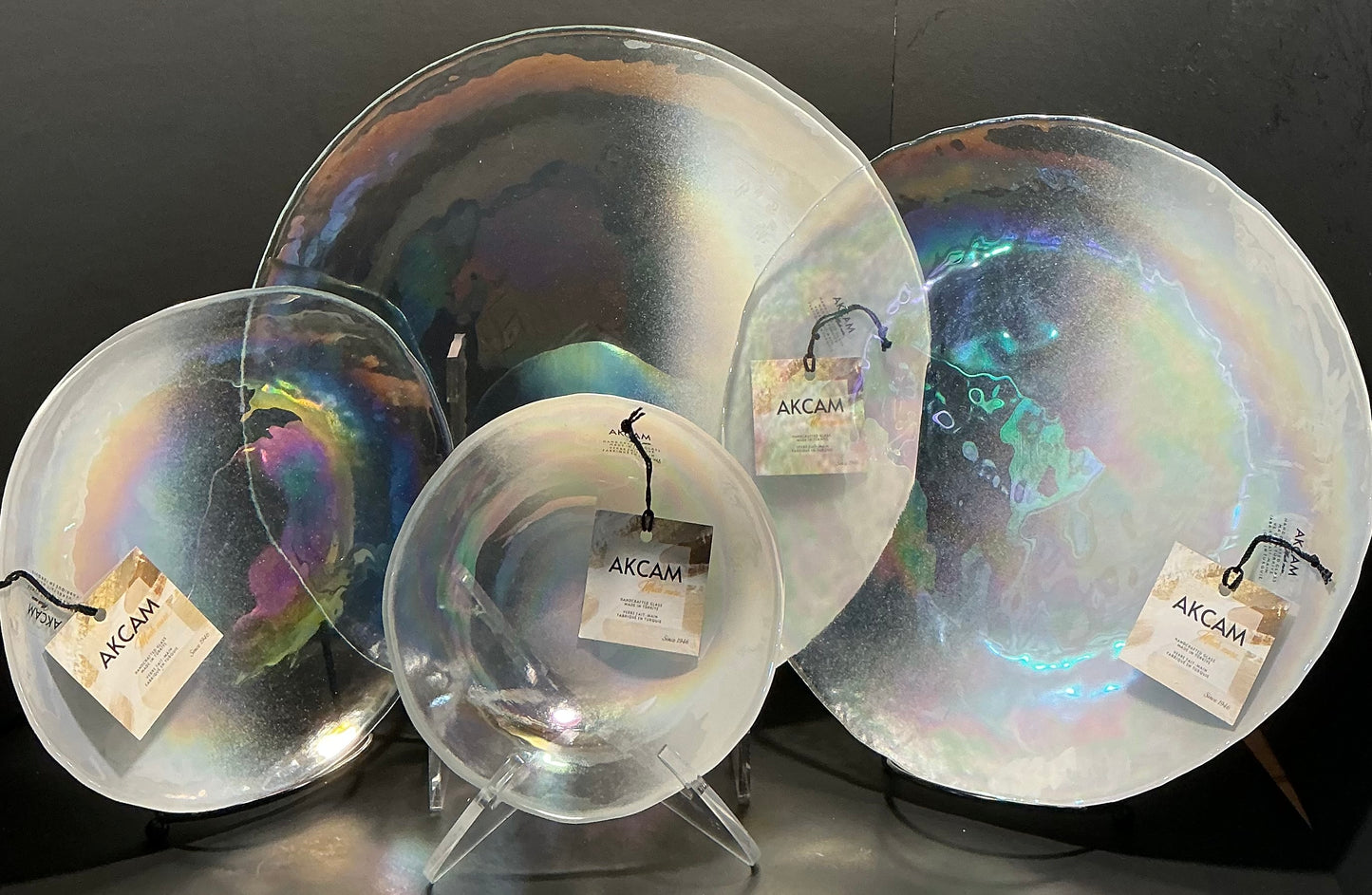 Akcam Iridescent Glass Set of 4 includes a  12” 10” 8” plates and a 6” bowl, which are handmade in Turkey known with their shimmering opal-like finish that changes color with light.