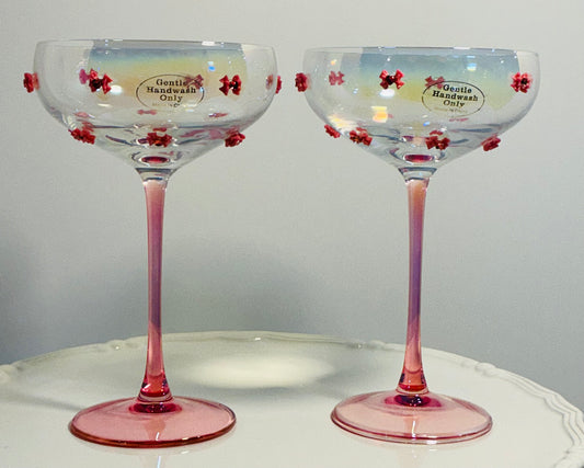 Set of 2 Iridescent pink coupe glasses feature a stem-to-base ombré effect decorated w/red bows 7”