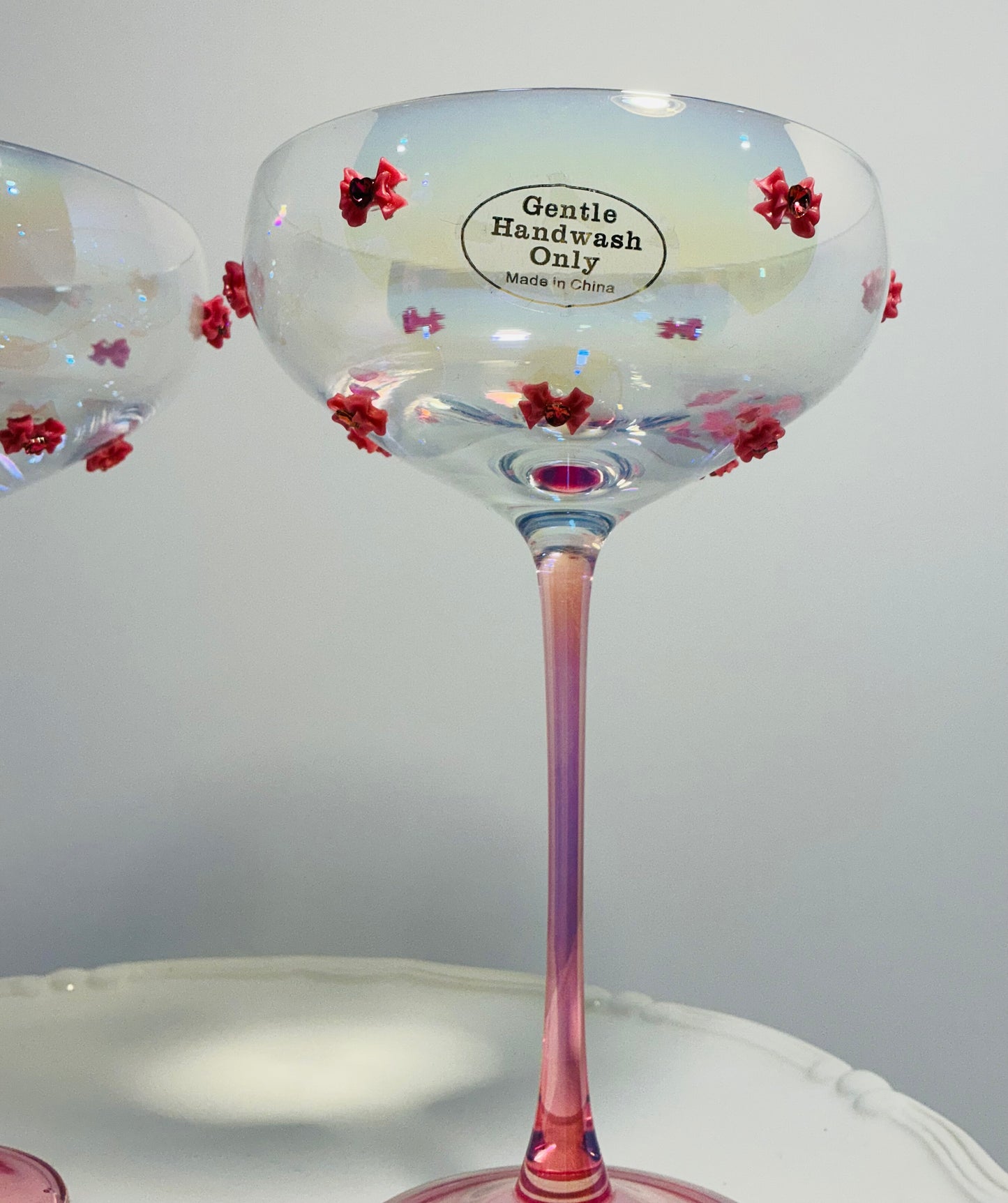 Set of 2 Iridescent pink coupe glasses feature a stem-to-base ombré effect decorated w/red bows 7”