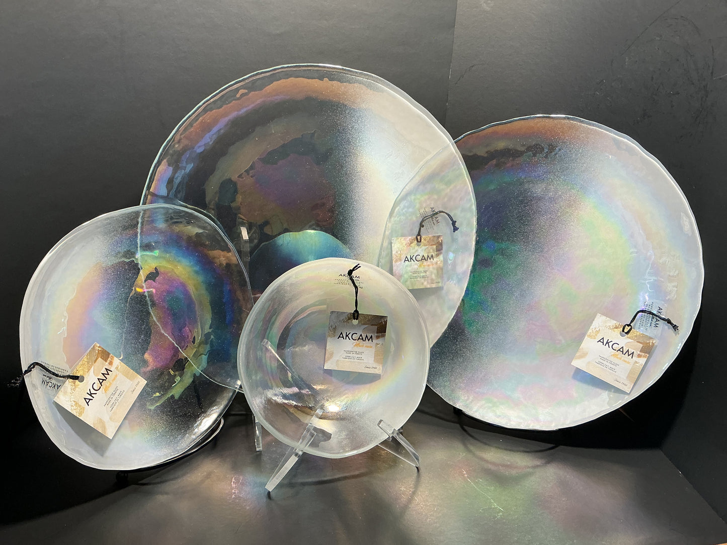Akcam Iridescent Glass Set of 4 includes a  12” 10” 8” plates and a 6” bowl, which are handmade in Turkey known with their shimmering opal-like finish that changes color with light.